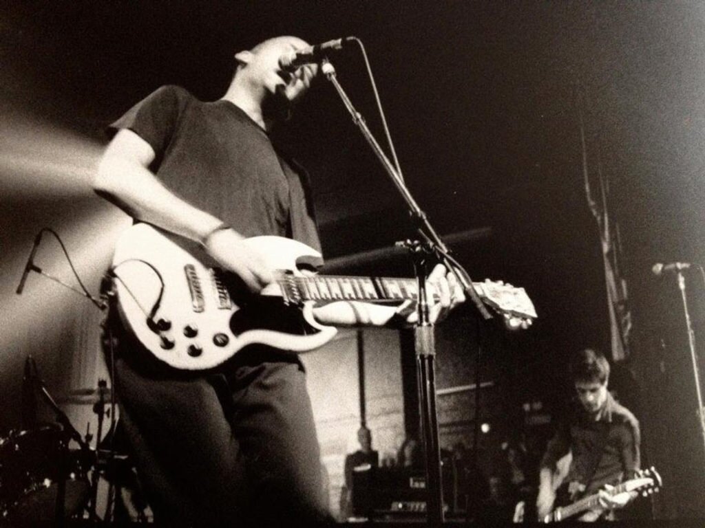Photo of Fugazi performing on stage in Lido, Leuven